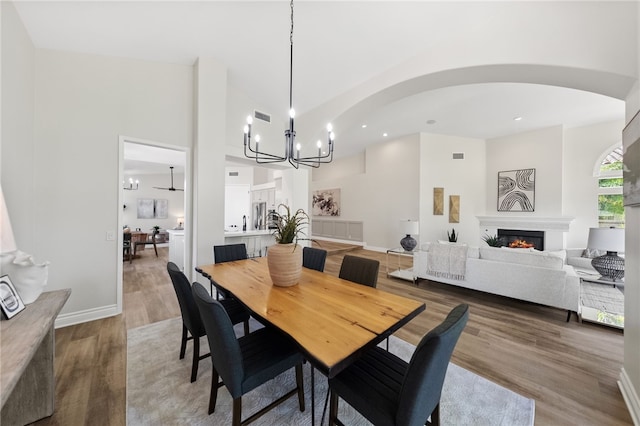dining area with wood finished floors, a chandelier, arched walkways, visible vents, and recessed lighting