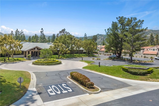 view of home's community featuring uncovered parking, a mountain view, and a yard