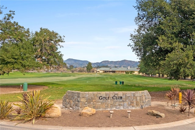view of property's community with a lawn, view of golf course, and a mountain view