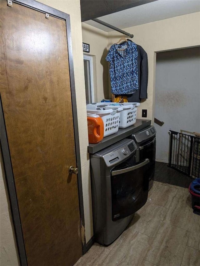 laundry room featuring washing machine and clothes dryer, wood finished floors, and laundry area