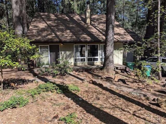 view of front of home with a chimney and roof with shingles