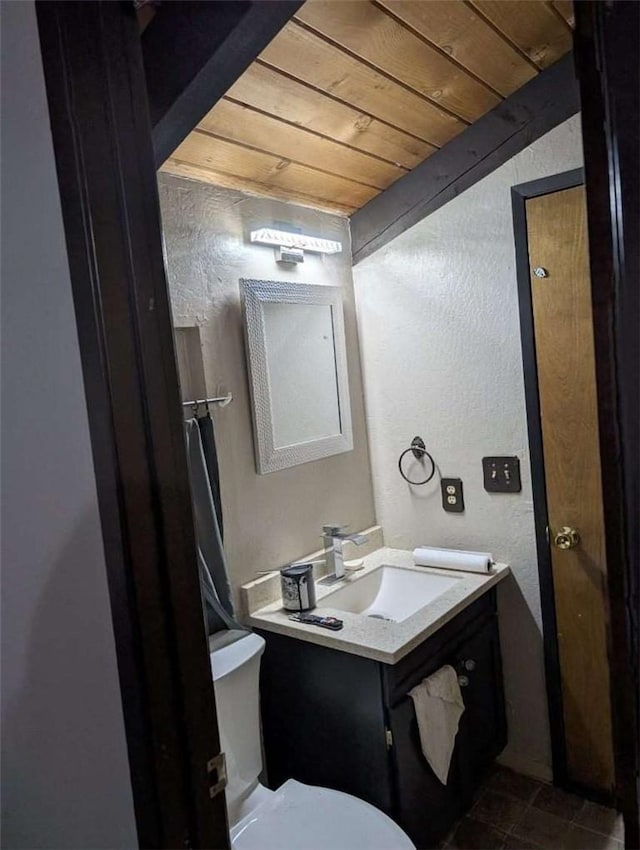 half bath featuring wood ceiling, toilet, a textured wall, and vanity