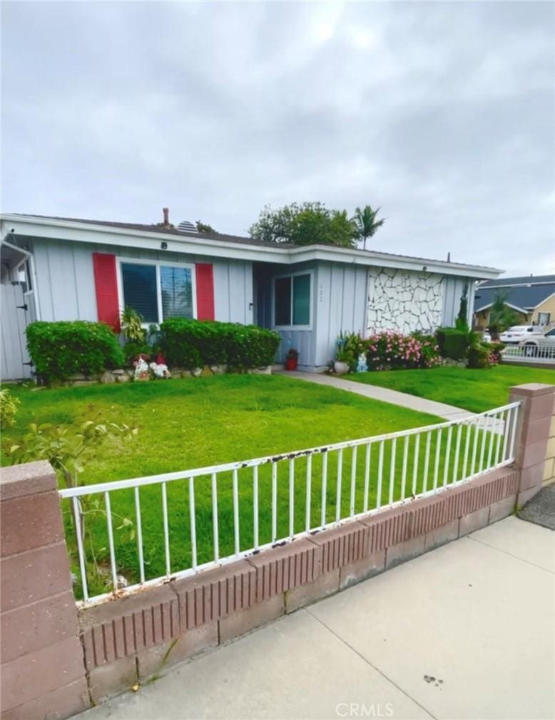 single story home with board and batten siding, fence private yard, and a front yard