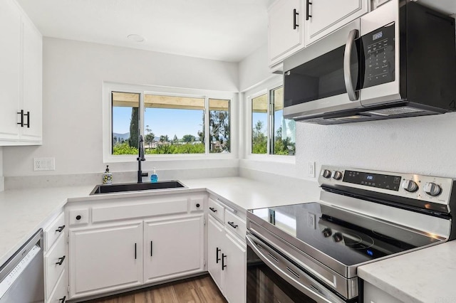 17607 Pomerado Rd Unit 204, San Diego, CA 92128 - kitchen with stainless steel appliances, a sink, white cabinetry, wood finished floors, and light countertops