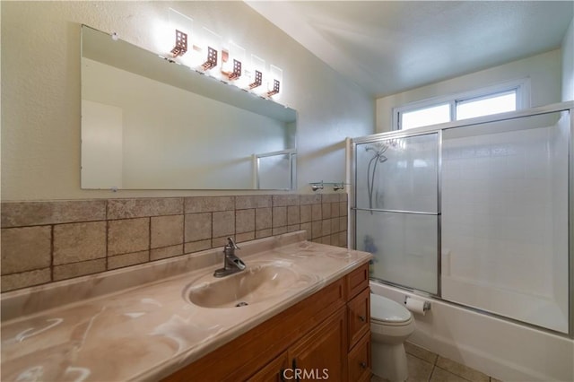 full bath featuring vanity, tile patterned flooring, combined bath / shower with glass door, and toilet