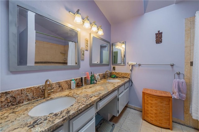 full bath featuring a sink, tile patterned floors, baseboards, and double vanity