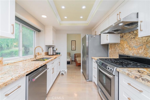 kitchen with under cabinet range hood, stainless steel appliances, white cabinets, and a sink