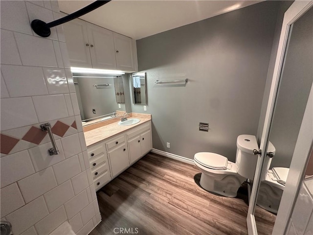bathroom with toilet, wood finished floors, and vanity
