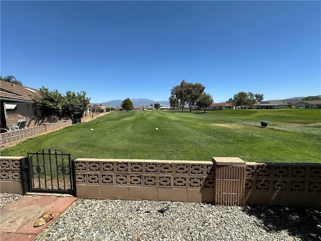 view of property's community featuring a yard, a mountain view, fence, and a gate