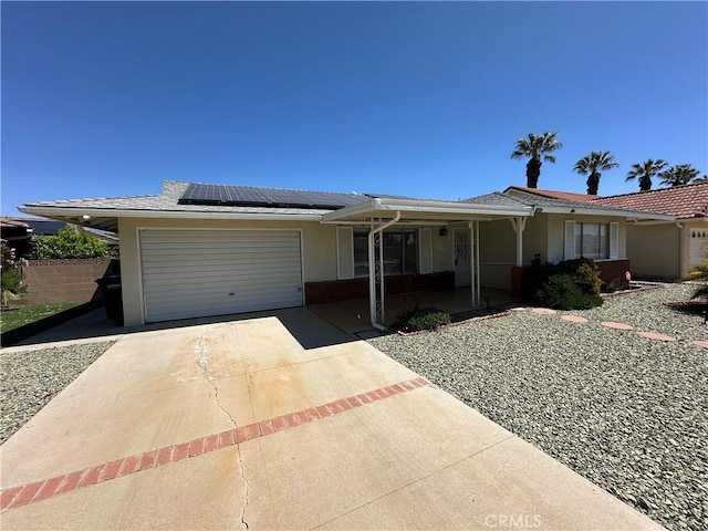 single story home with roof mounted solar panels, concrete driveway, a garage, and stucco siding