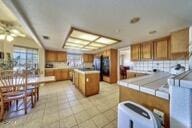 9975 Custer Ave, Lucerne Valley, CA 92356 - kitchen with light countertops, a peninsula, brown cabinets, backsplash, and light tile patterned flooring