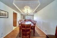 9975 Custer Ave, Lucerne Valley, CA 92356 - dining area with a chandelier, a tray ceiling, baseboards, and wood finished floors