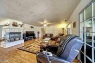 9975 Custer Ave, Lucerne Valley, CA 92356 - living room featuring a ceiling fan and a fireplace with raised hearth
