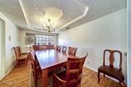 9975 Custer Ave, Lucerne Valley, CA 92356 - dining room featuring a tray ceiling, baseboards, a notable chandelier, and wood finished floors