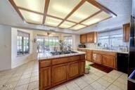 9975 Custer Ave, Lucerne Valley, CA 92356 - kitchen with stovetop, brown cabinets, light countertops, and light tile patterned flooring