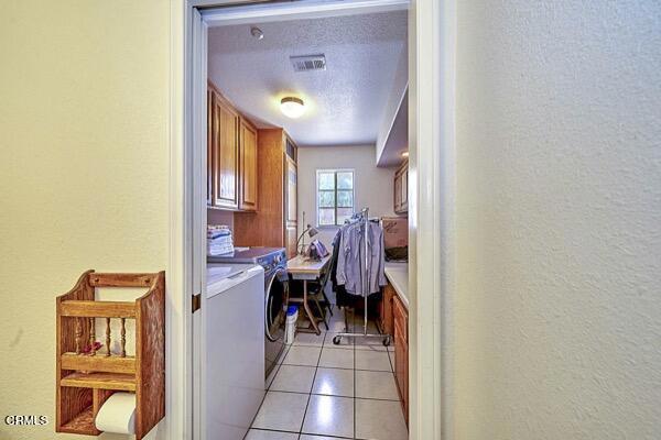 9975 Custer Ave, Lucerne Valley, CA 92356 - clothes washing area with separate washer and dryer, a textured wall, light tile patterned flooring, visible vents, and cabinet space