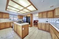 9975 Custer Ave, Lucerne Valley, CA 92356 - kitchen with backsplash, brown cabinetry, a center island, and light tile patterned floors