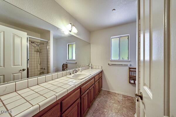9975 Custer Ave, Lucerne Valley, CA 92356 - full bathroom featuring baseboards, tiled shower, and vanity