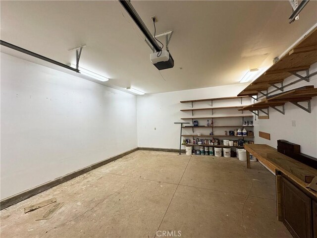 24250 Pacific Heights Dr, Westport, CA 95488 - garage featuring baseboards, a garage door opener, and a workshop area