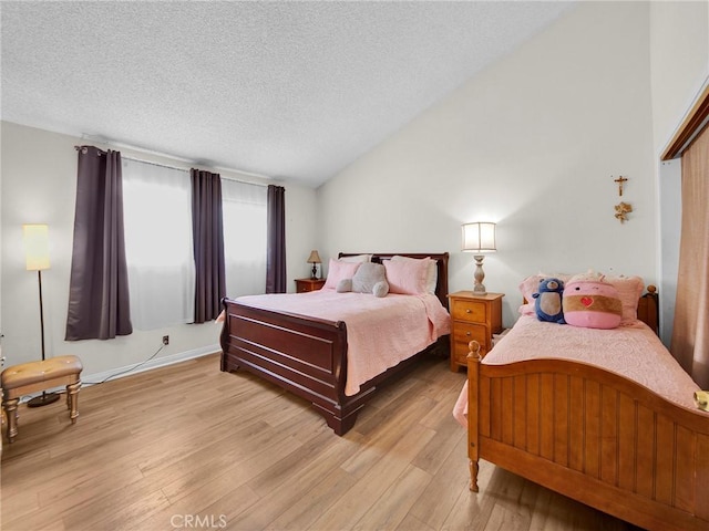 bedroom featuring light wood-type flooring, a textured ceiling, and vaulted ceiling