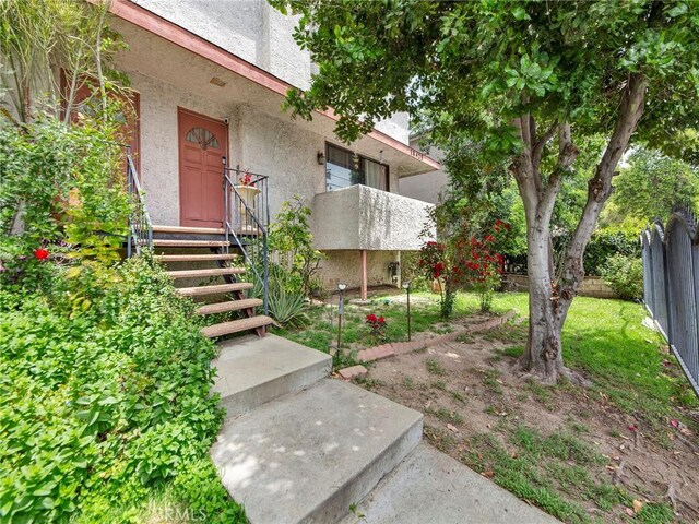 view of exterior entry with stucco siding and fence