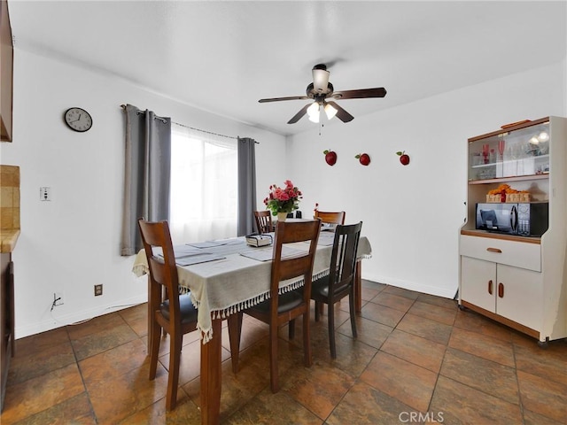 dining space featuring ceiling fan and baseboards