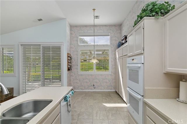 kitchen with visible vents, light countertops, white appliances, and wallpapered walls