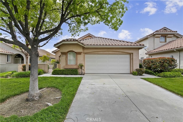 mediterranean / spanish-style home with stucco siding, a front lawn, a tile roof, a garage, and concrete driveway