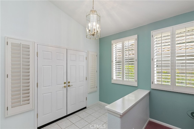 foyer entrance featuring a chandelier, light tile patterned flooring, and baseboards