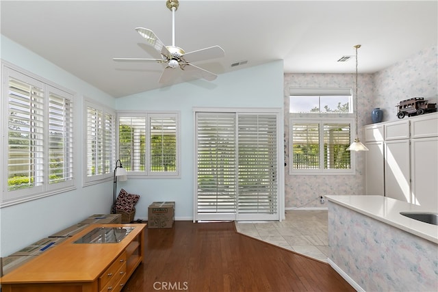interior space featuring wood finished floors, vaulted ceiling, a ceiling fan, and visible vents