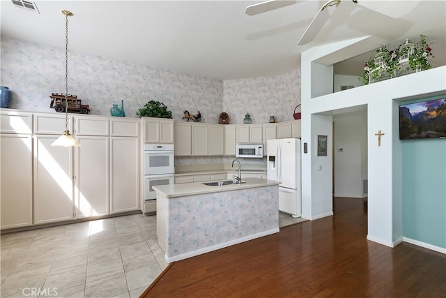 kitchen featuring a sink, light countertops, ceiling fan, white appliances, and pendant lighting