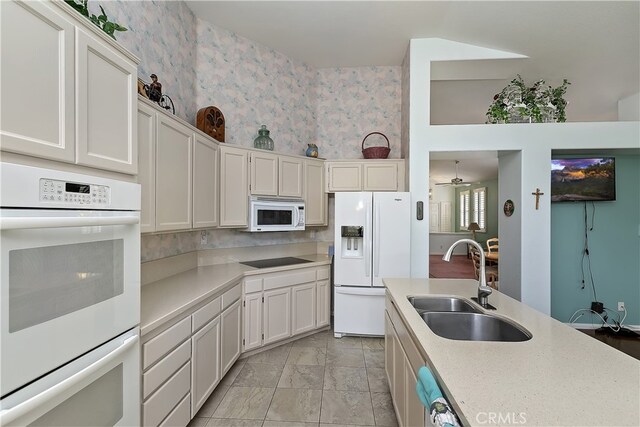 kitchen featuring white appliances, light countertops, a ceiling fan, white cabinetry, and a sink