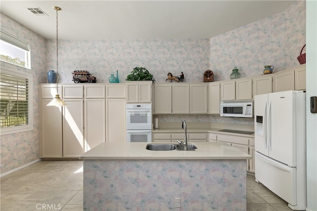 kitchen with wallpapered walls, white appliances, light countertops, visible vents, and a sink