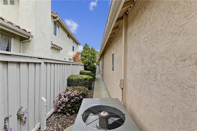 view of side of property with central AC, ac unit, fence, and stucco siding