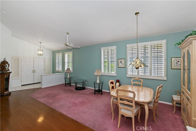 dining area featuring baseboards, vaulted ceiling, ceiling fan with notable chandelier, and wood finished floors