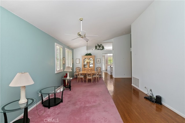 living area featuring baseboards, vaulted ceiling, visible vents, ceiling fan, and wood finished floors