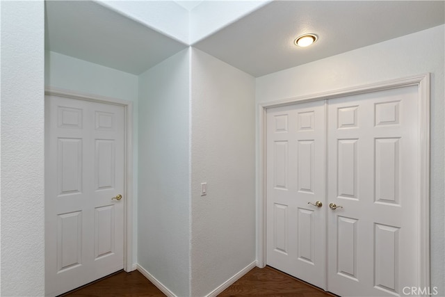 hall featuring dark wood-type flooring and baseboards