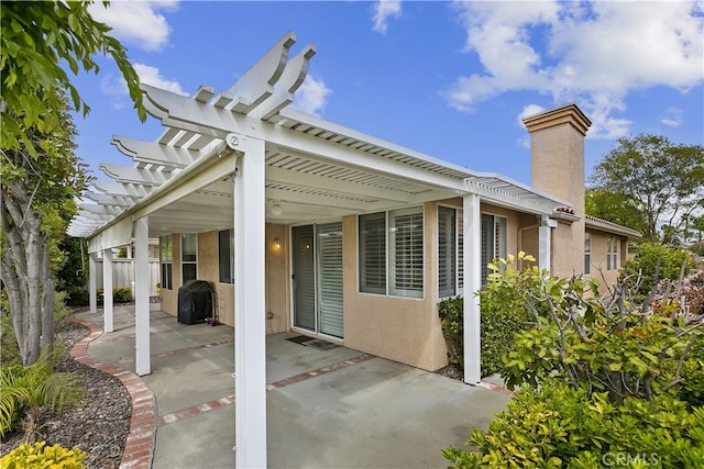 exterior space featuring a chimney, stucco siding, a patio, and a pergola
