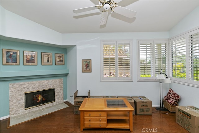 interior space featuring a fireplace with flush hearth, dark wood-style flooring, baseboards, and ceiling fan
