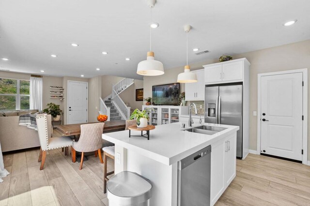 1751 Whitmore Loop, Chula Vista, CA 91913 - kitchen with appliances with stainless steel finishes, a sink, light wood-style flooring, an island with sink, and light countertops