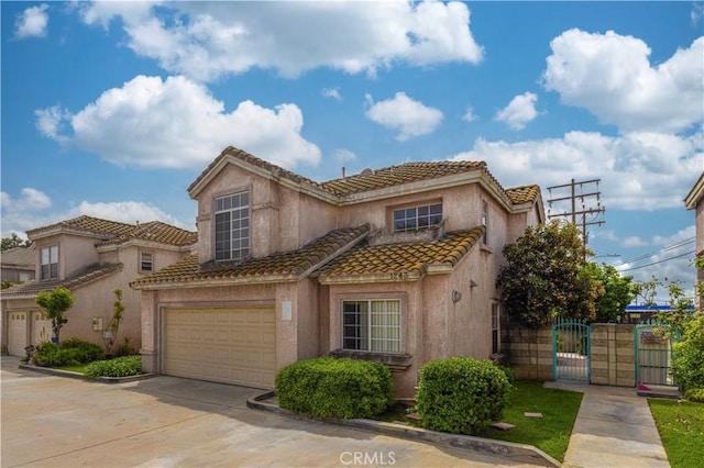 view of front of home with concrete driveway, stucco siding, a garage, a tiled roof, and a gate