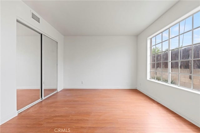 unfurnished bedroom with visible vents, baseboards, light wood-type flooring, and a closet