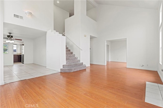 unfurnished living room featuring light wood finished floors, high vaulted ceiling, ceiling fan, and visible vents