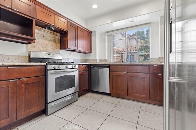 kitchen featuring light tile patterned floors, light stone countertops, recessed lighting, a sink, and stainless steel appliances