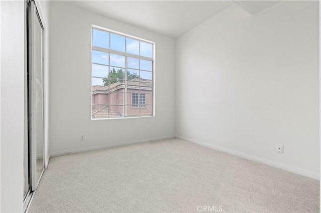 empty room featuring light carpet and baseboards