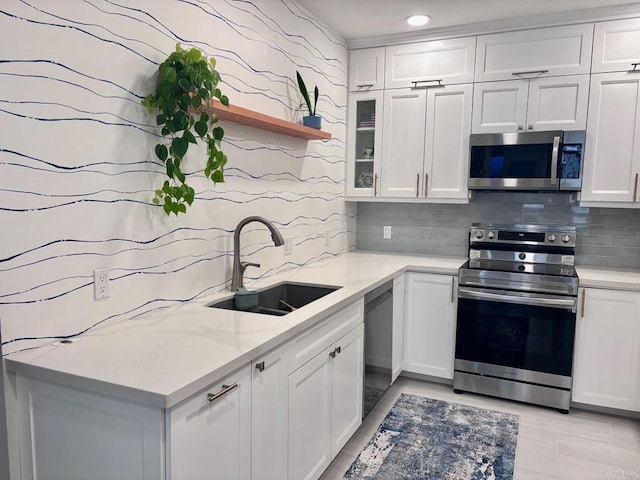 kitchen featuring a sink, tasteful backsplash, white cabinets, and appliances with stainless steel finishes
