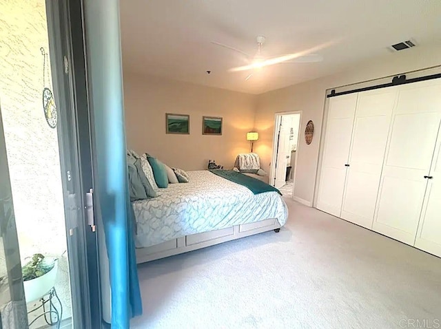 carpeted bedroom featuring a barn door, a closet, and visible vents