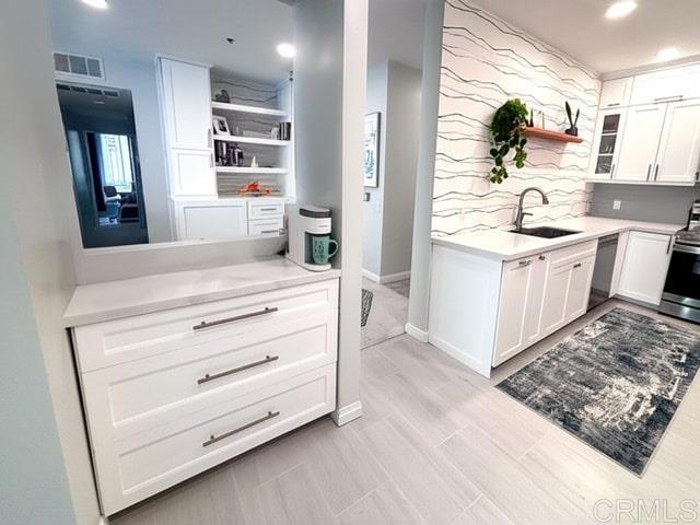 kitchen with dishwashing machine, a sink, open shelves, visible vents, and electric stove