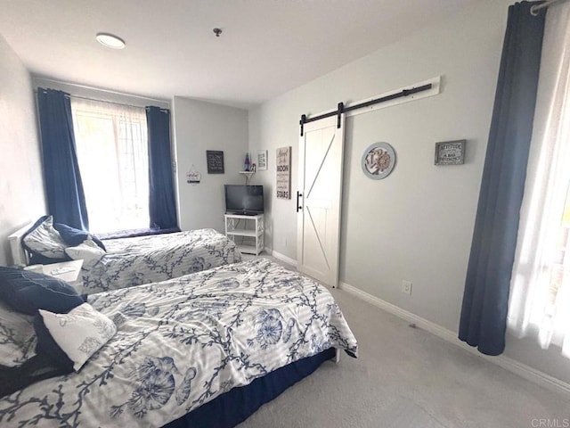 carpeted bedroom featuring a barn door and baseboards