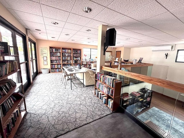 interior space featuring an AC wall unit and a paneled ceiling